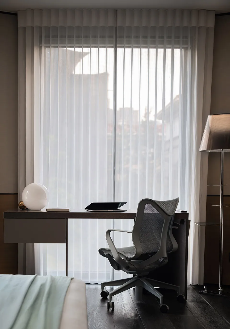 A minimalist modern office space featuring glass walls, wooden desk, and ergonomic chair.