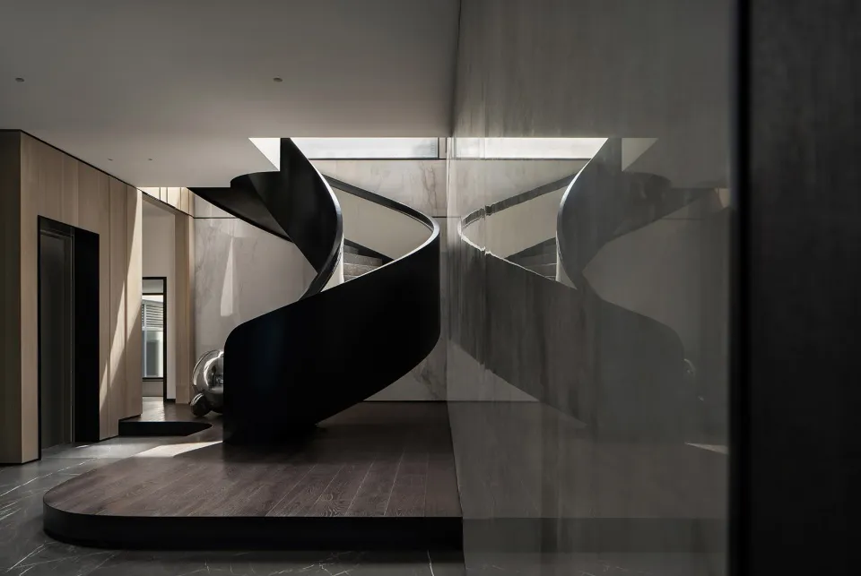 Modern black metal staircase with marble floor and glass walls.