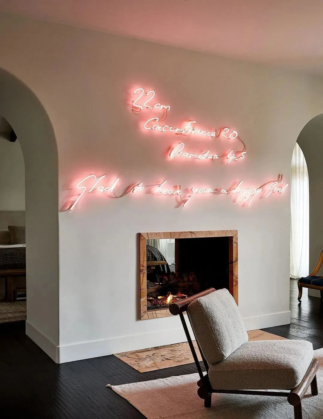 A modern living room featuring neon lights spelling out literature-related phrases above a fireplace.