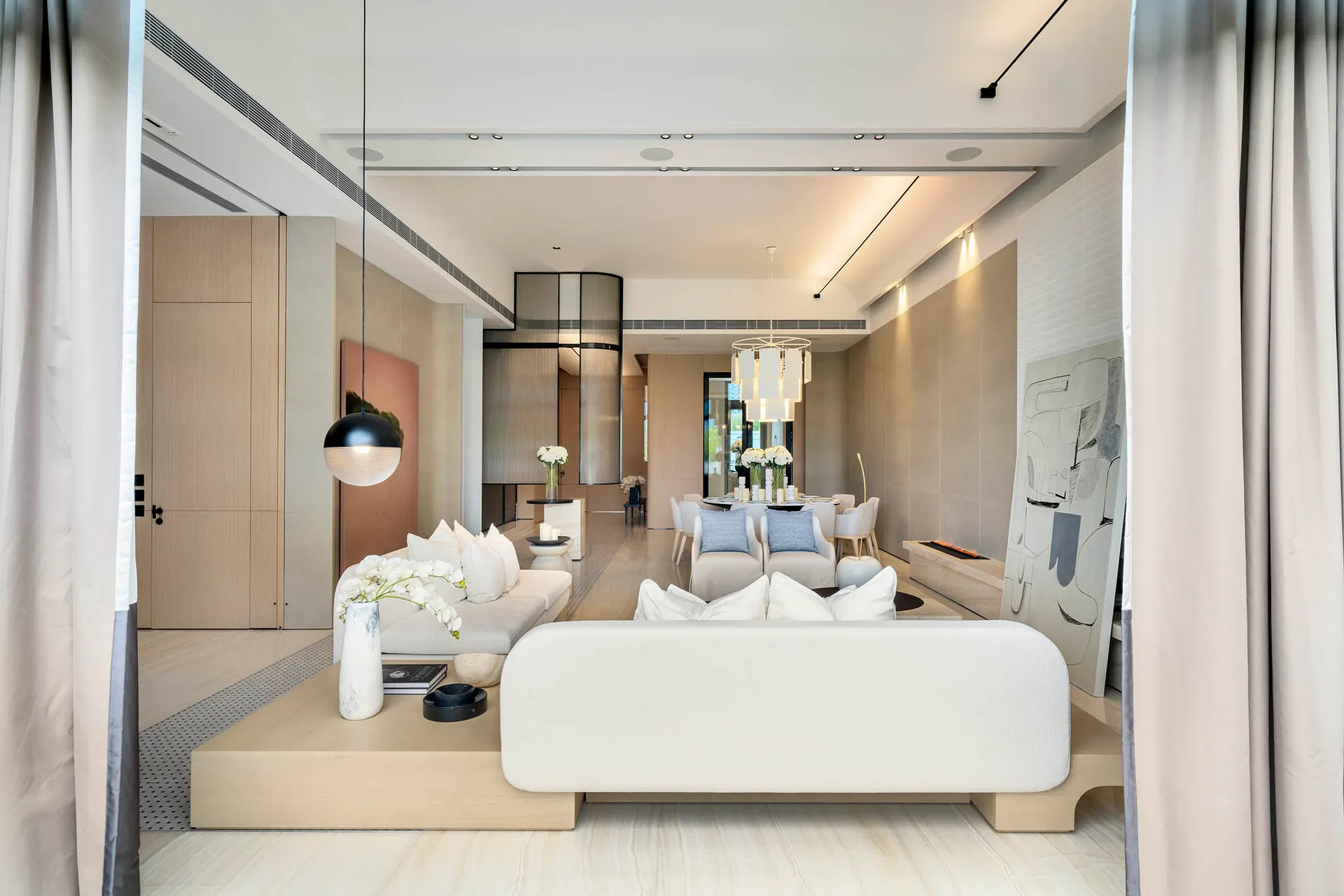 A minimalist living and dining room with marble and wood elements.