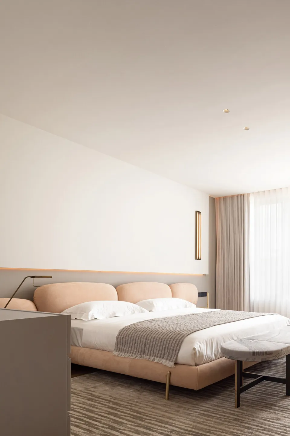 Modern bedroom featuring soft, neutral-toned bedding and furniture.