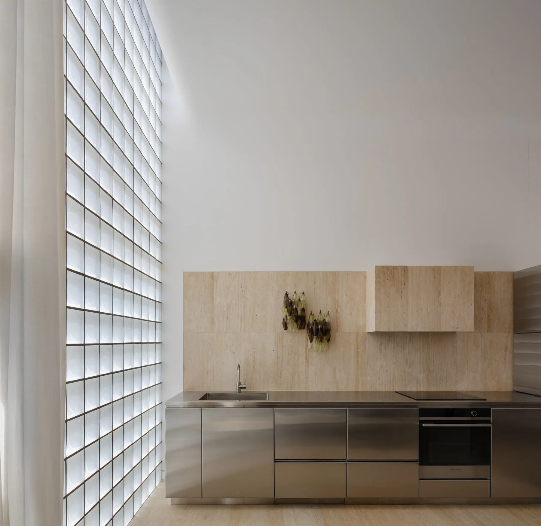 Modern minimalist kitchen featuring custom glass block partitions and stainless steel cabinetry and appliances.