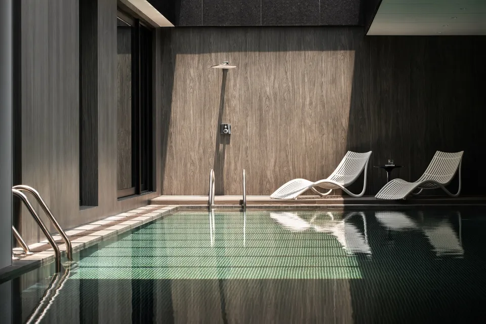 Indoor swimming pool with glass and concrete elements at a luxury resort hotel.