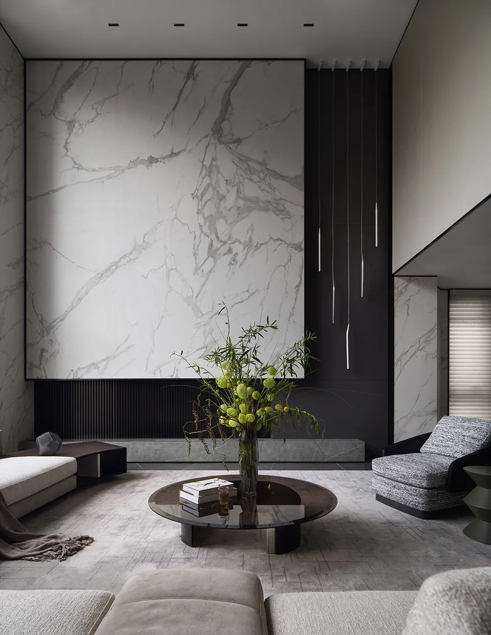 Modern living room featuring marble walls and a round coffee table with a greenery arrangement.