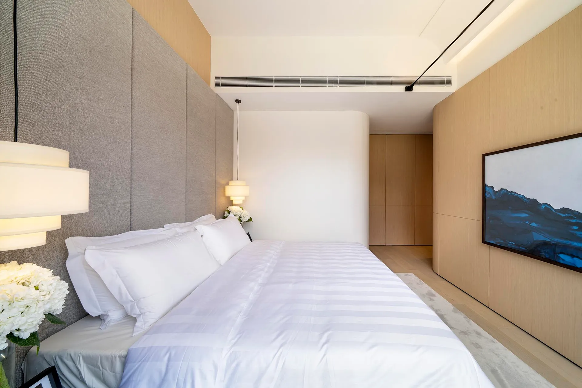 Modern bedroom with white sheets, minimalist decor, and wooden wall panels