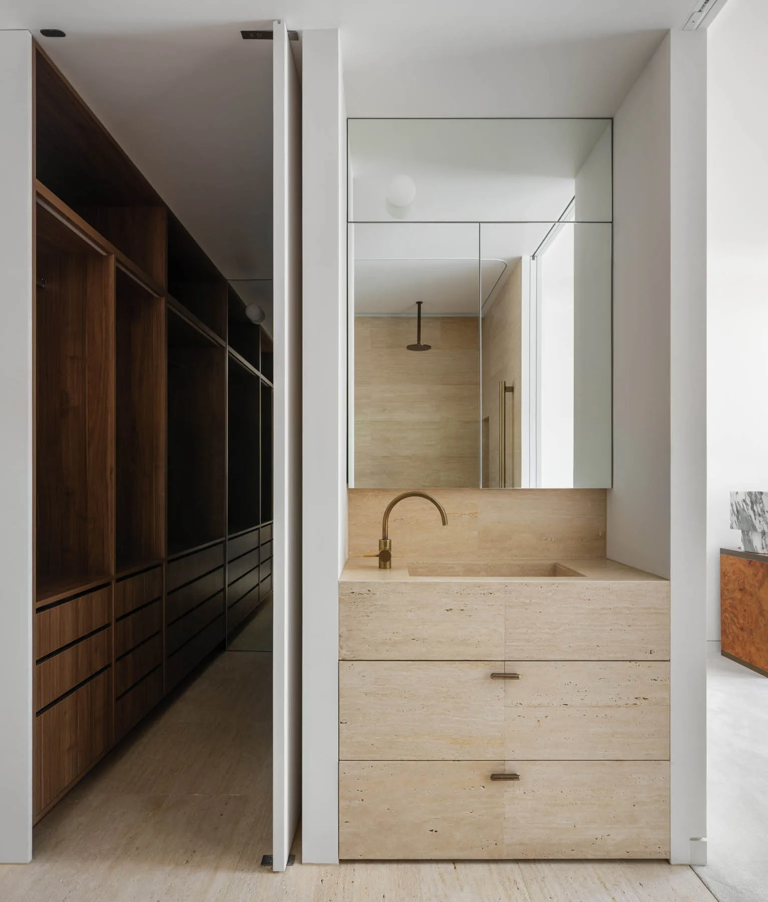 Modern minimalist bathroom featuring a stone vanity with a single basin sink and brass fixtures.