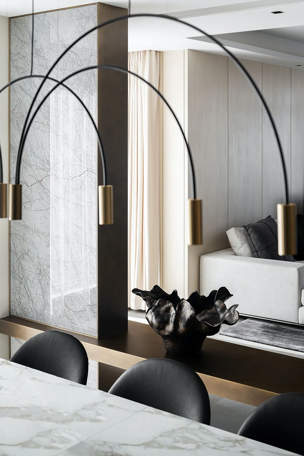 A modern dining room featuring a marble table, black leather chairs, and minimalist decor.