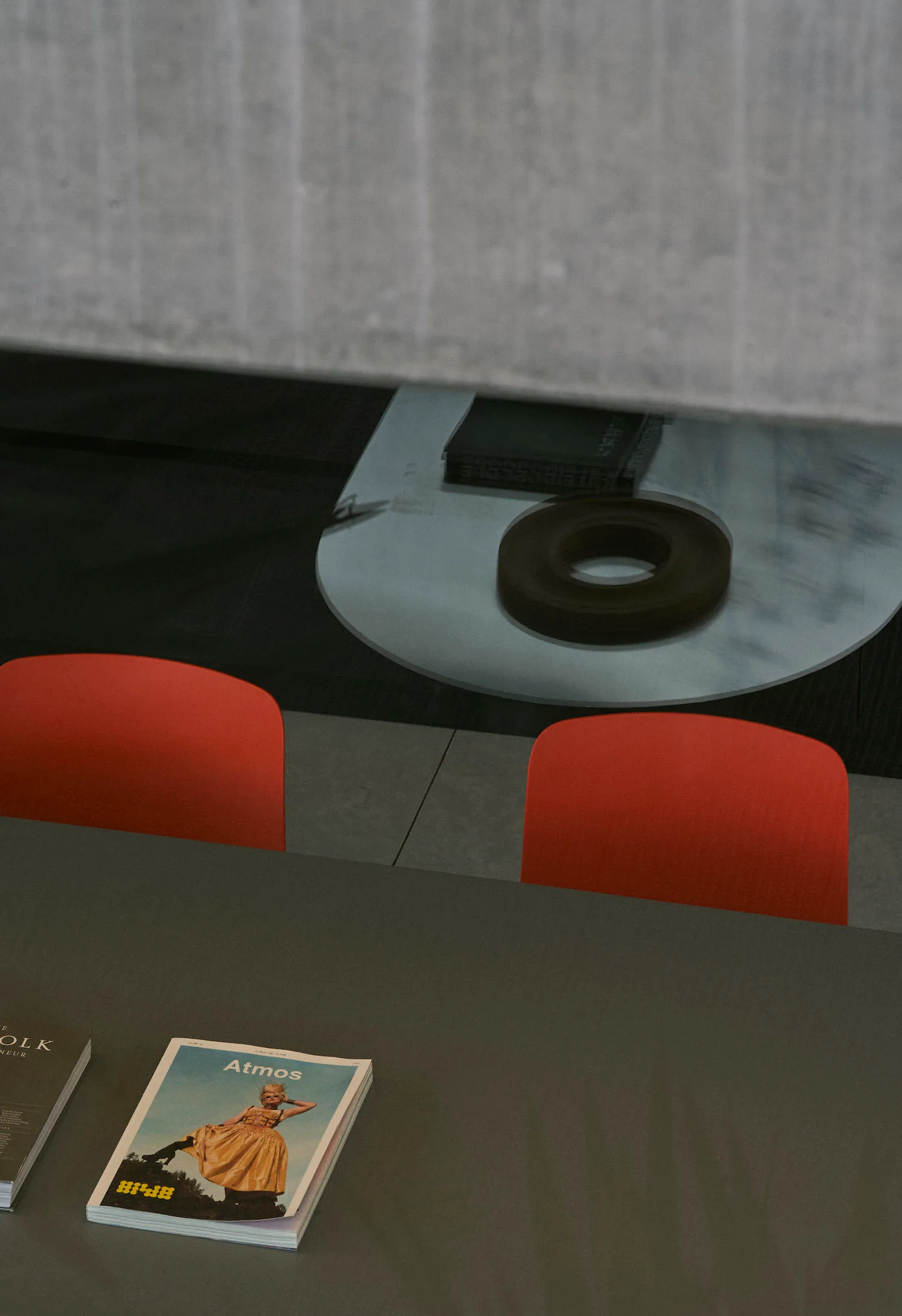 A magazine display with red chairs and a glass table, featuring a magazine titled 'Atmos'.