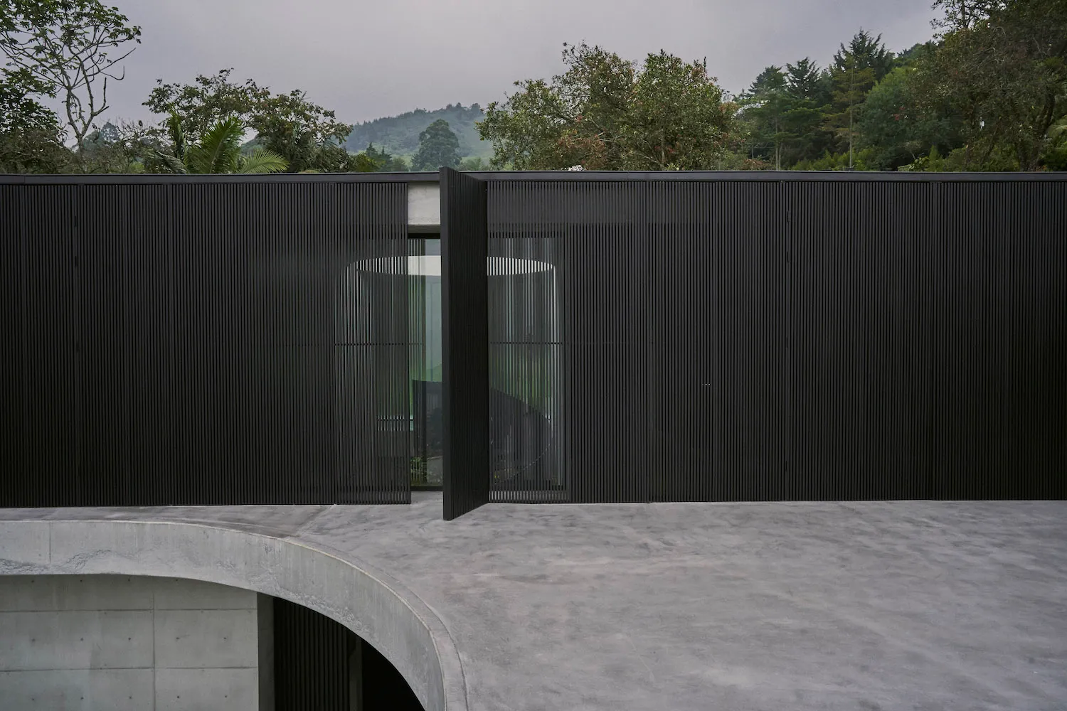 A modern house with a black striped fence and a minimalist design.