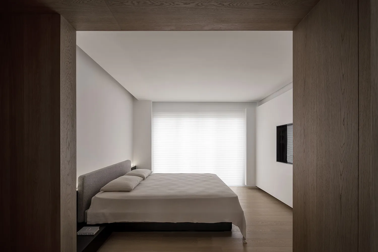 Modern minimalist bedroom with a wood floor and white walls.
