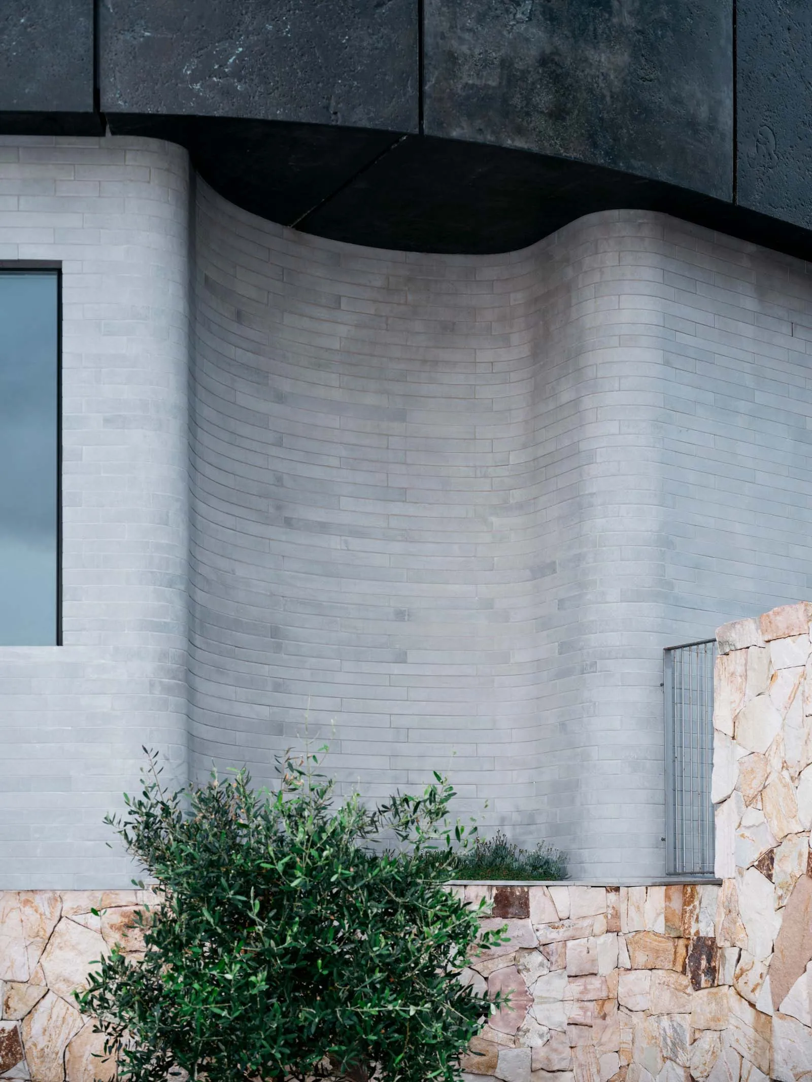 Concrete exterior of a modern minimalist building with curved walls and a high ceiling.
