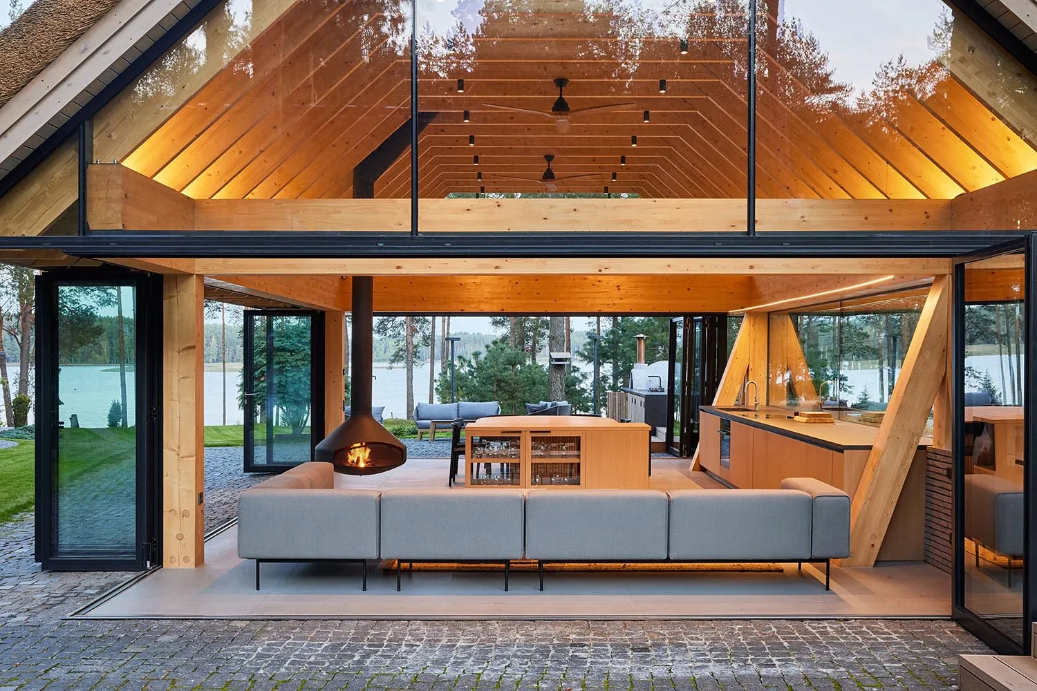 Modern residential interior with a wooden architecture and furnishings, featuring a lounge area with a fireplace and an open