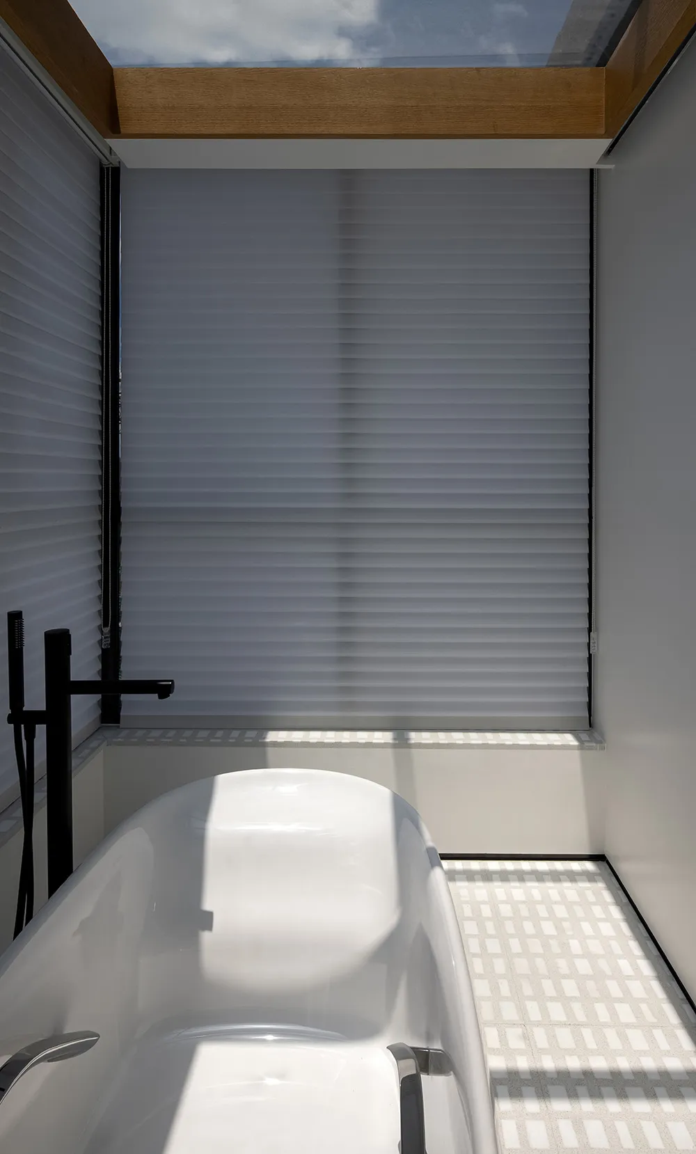 Modern bathroom with white tiles, glass shower enclosure, and freestanding tub.