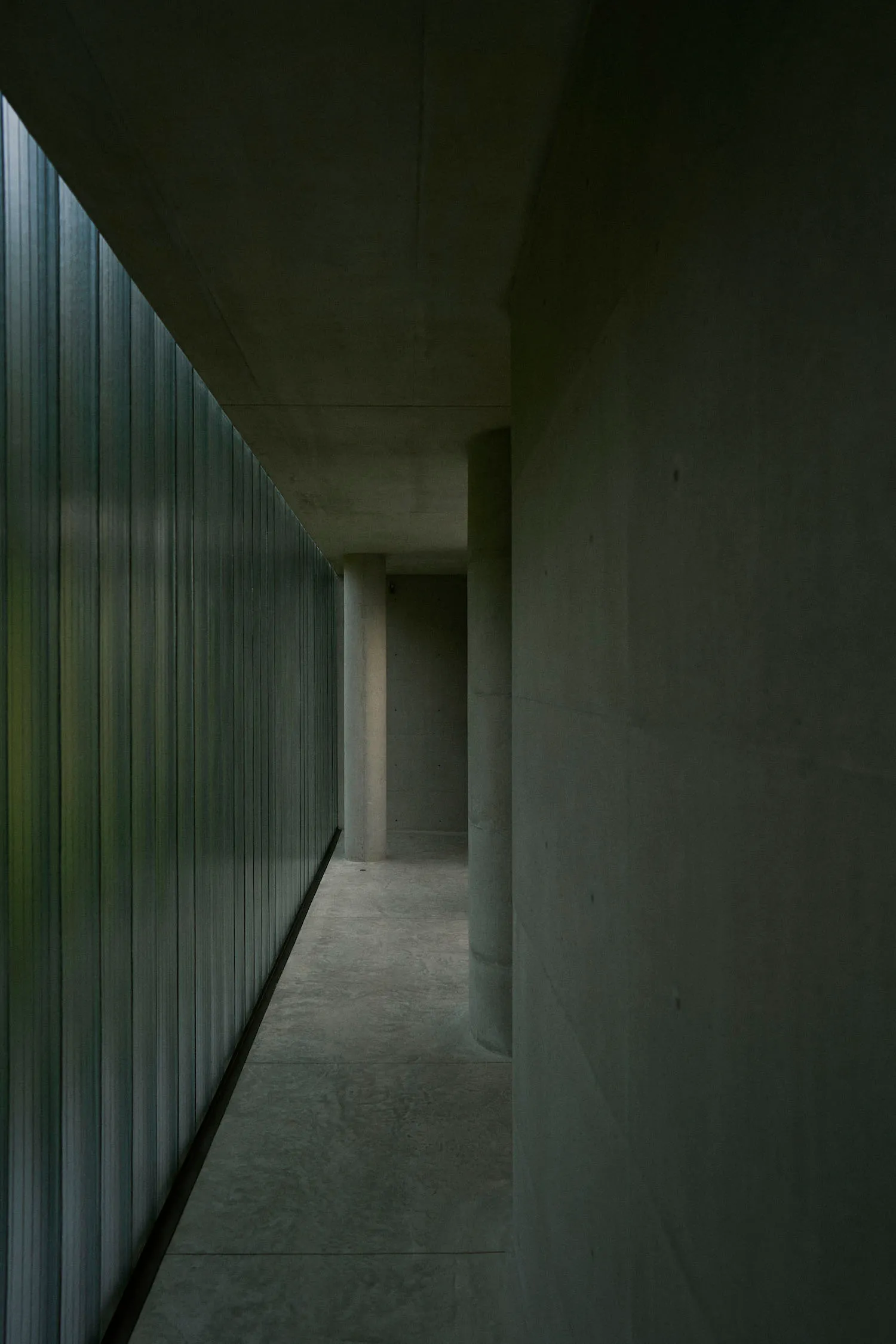 Minimalist design corridor featuring concrete and glass materials.