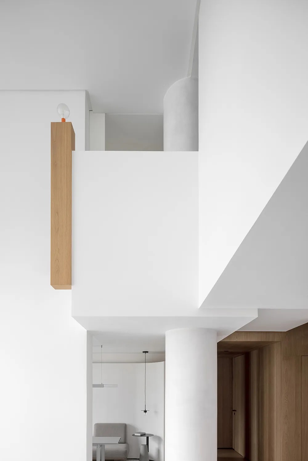 A minimalist modern interior featuring a concrete column and wooden beams.