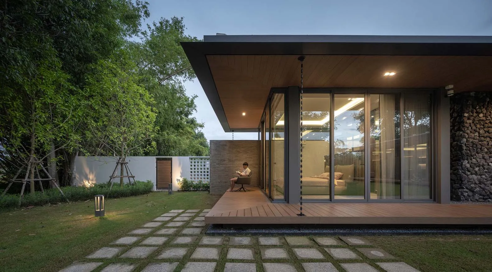 A modern minimalist house exterior with wood and concrete materials, featuring a covered patio and a well-maintained garden.