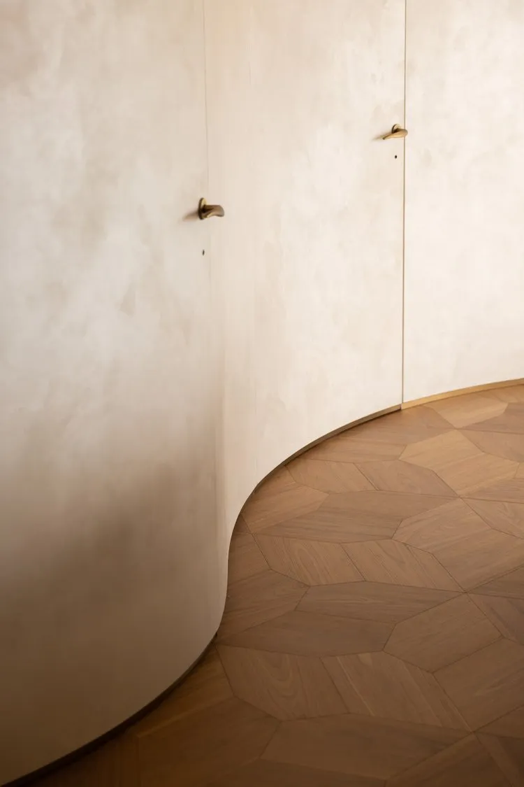 A minimalist interior featuring wood paneling on curved walls and geometric floor tiles.