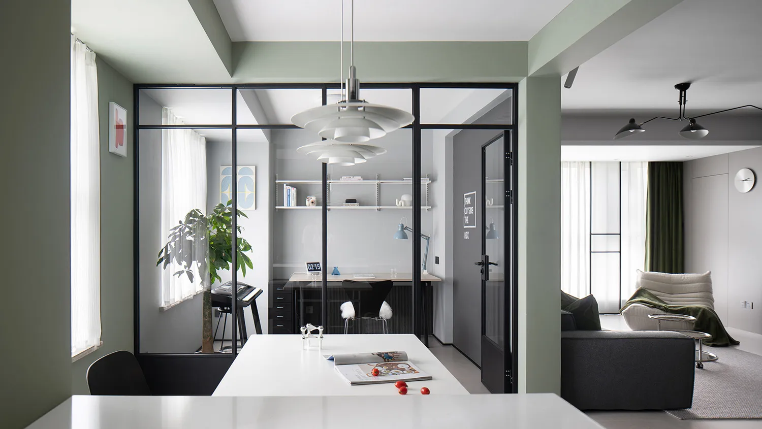 A modern living, dining, and office space featuring glass walls, cement flooring, and contemporary furniture.