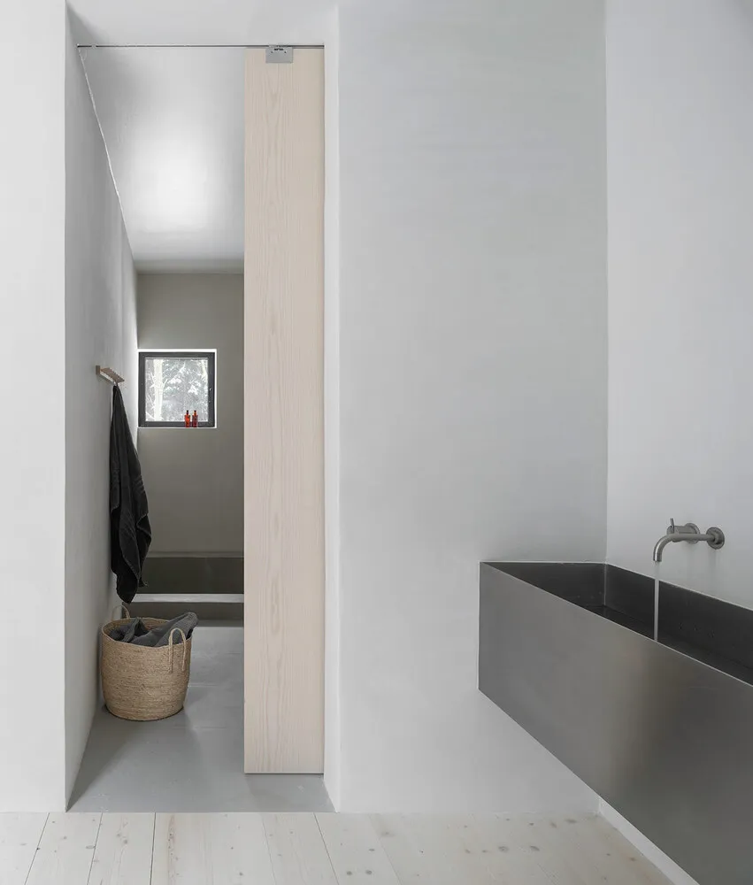 A minimalist bathroom featuring a concrete bathtub and a simple wooden door.