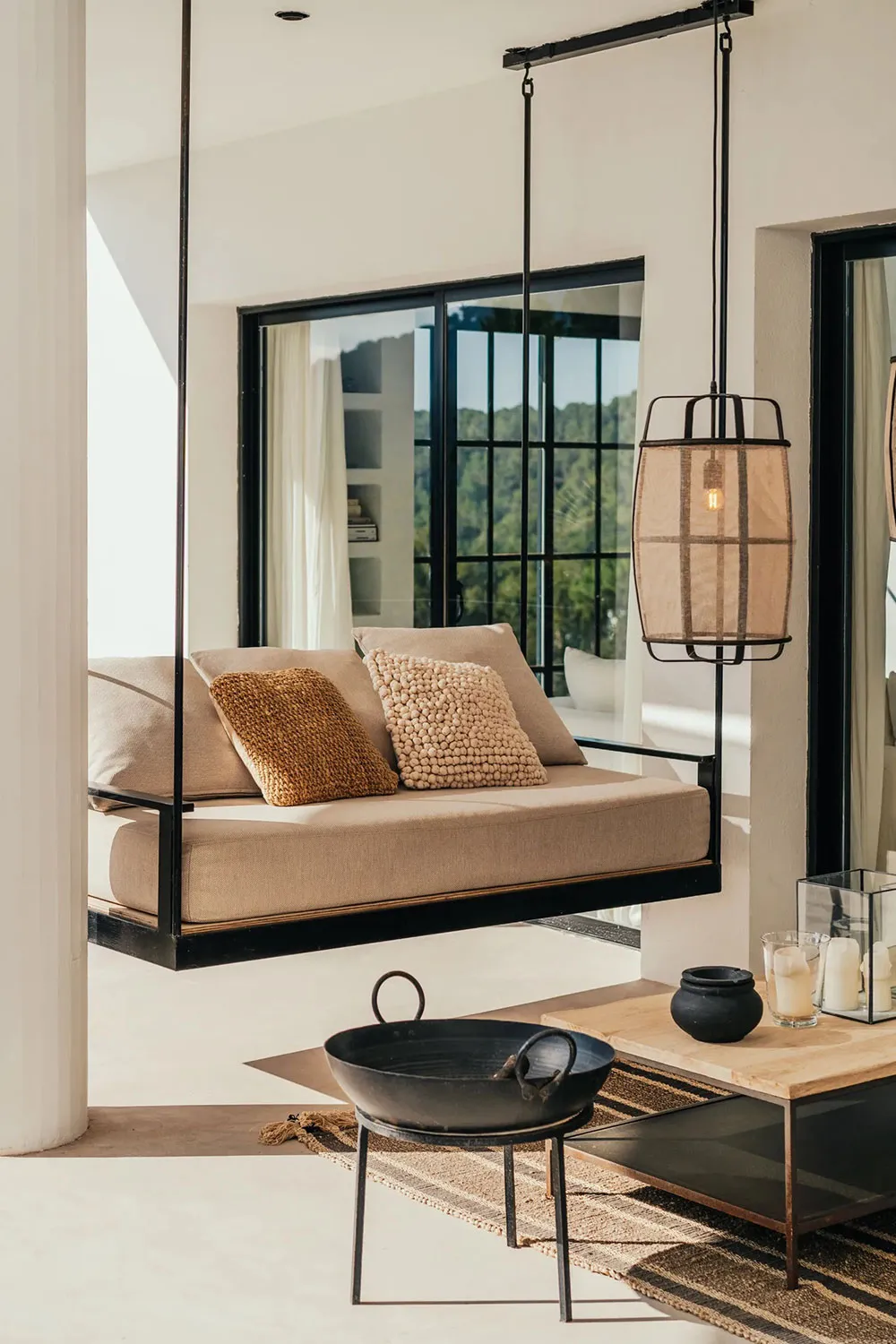 A minimalist living room featuring a floating sofa, hanging lantern light, and a wooden coffee table.