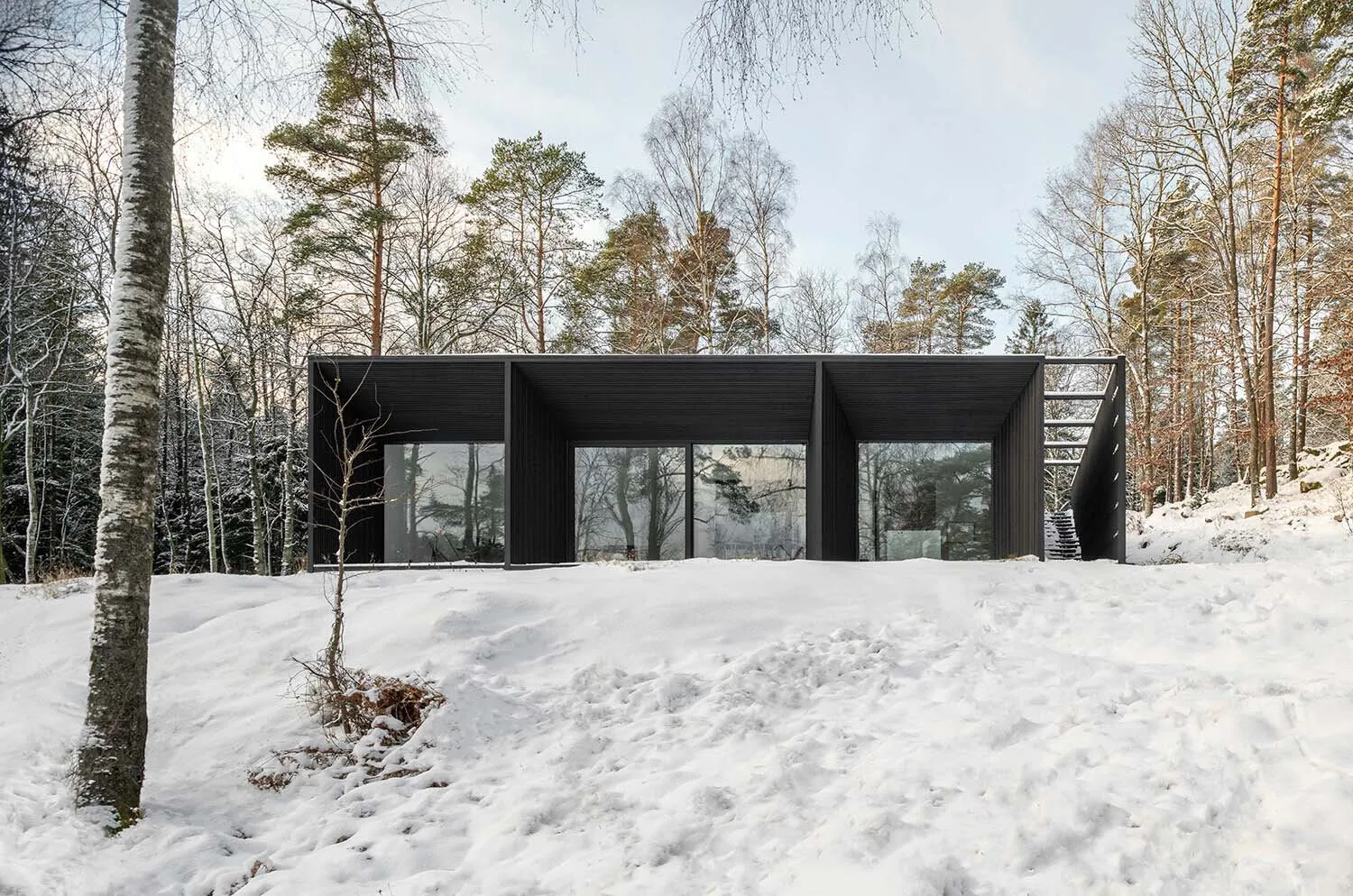 A modern black exterior house in a snowy winter landscape.