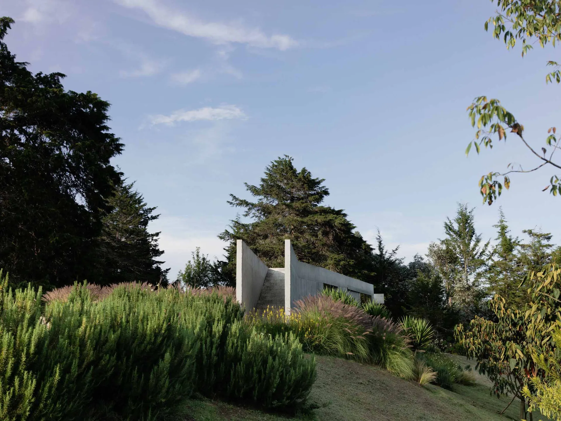 A modern landscape featuring concrete structures surrounded by greenery and trees.