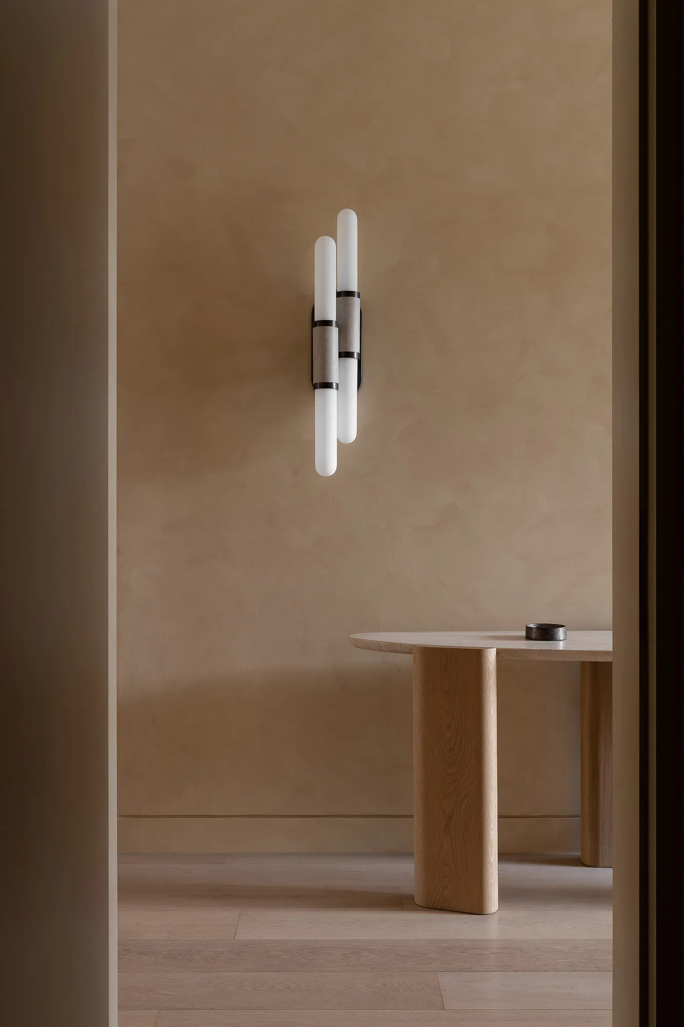 A minimalist interior showcasing wooden elements, concrete accents, and modern lighting against a beige textured wall.