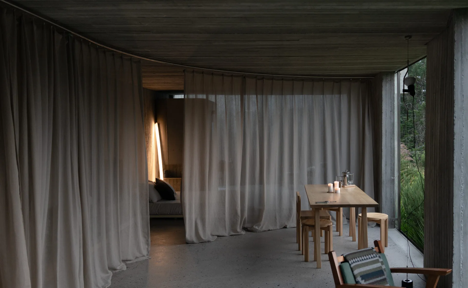 A minimalist living space featuring textured curtains and a warm, soft lighting setup.