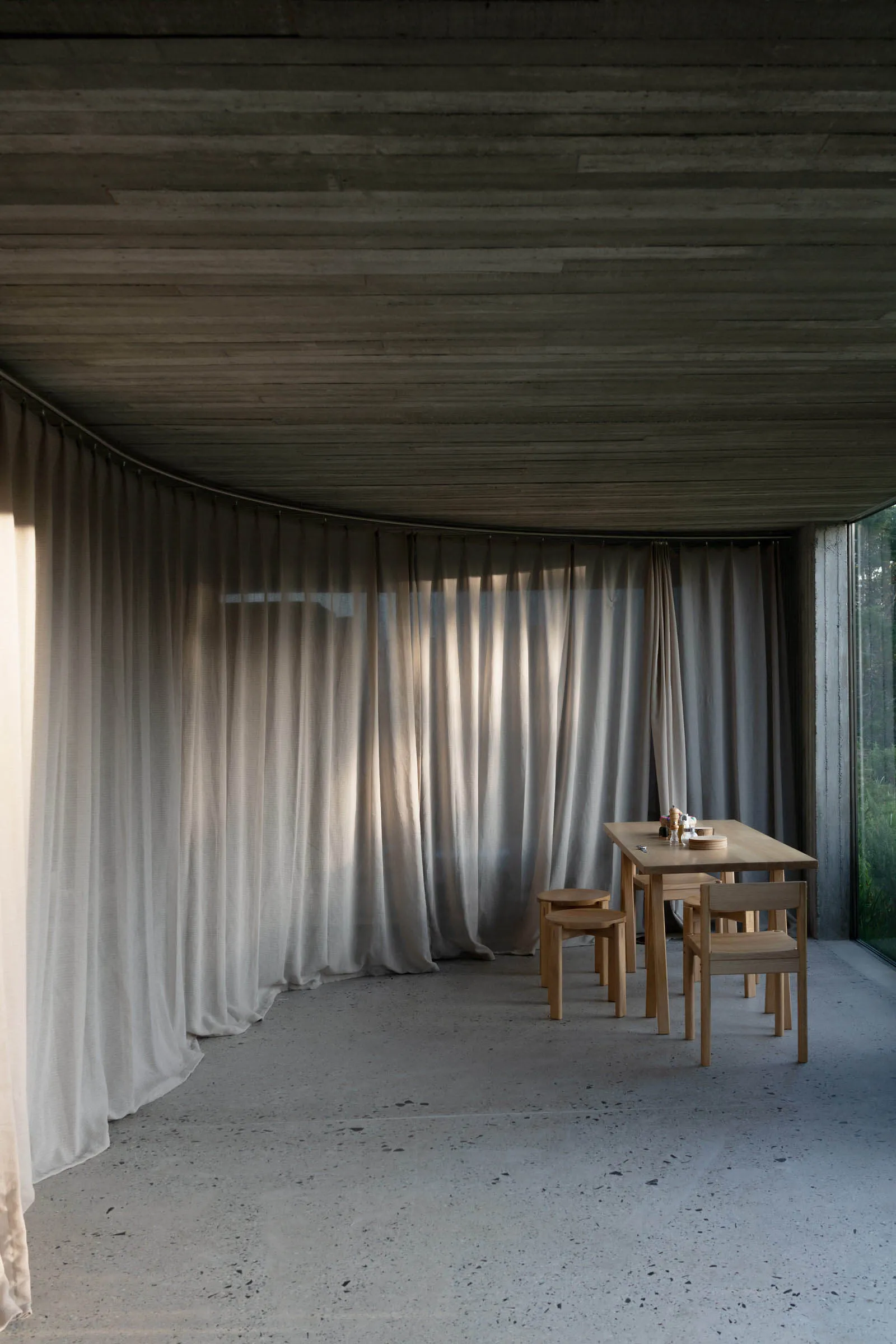 A sleek, modern dining room with a wooden table and chairs, featuring textured linen curtains and a wooden ceiling with horiz