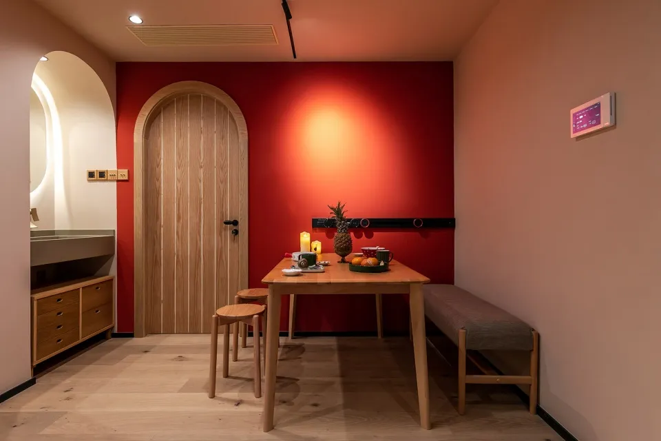 Modern minimalist dining room with wood elements and red accent wall.