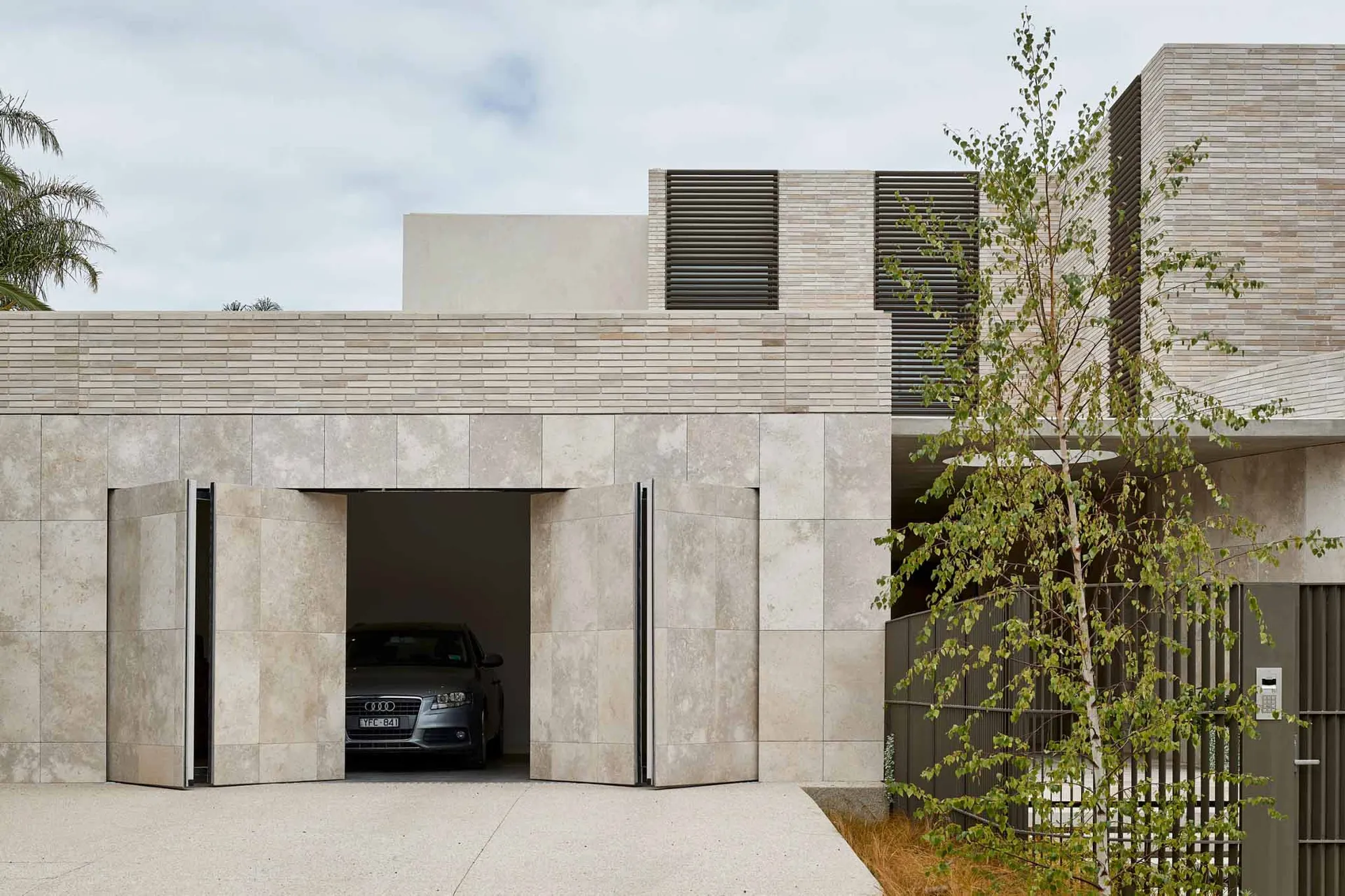 現代建築住宅,設有混凝土入口大門,內停放一輛汽車。