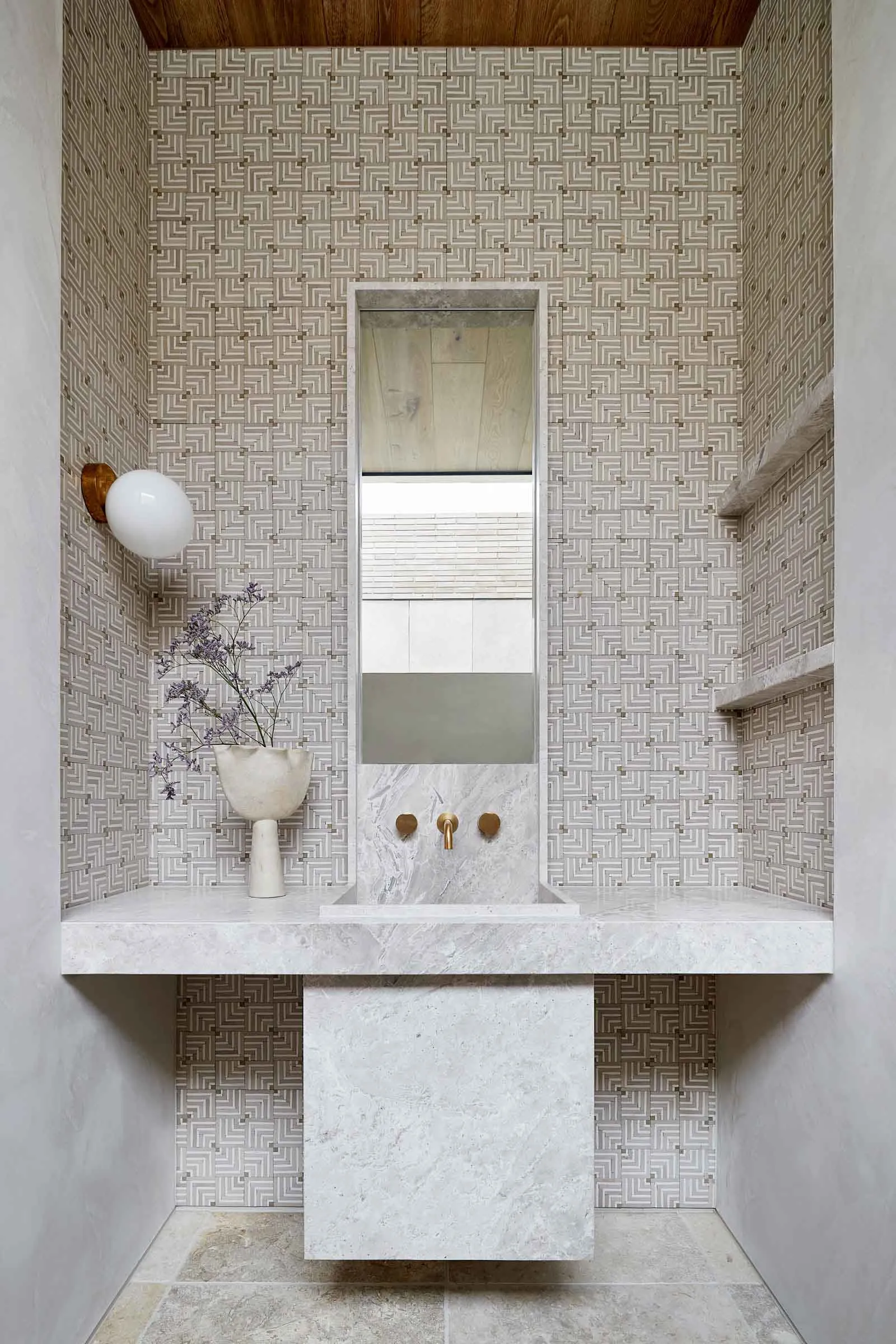 A modern bathroom with marble tiles, a floating sink, and geometric wall tiles.