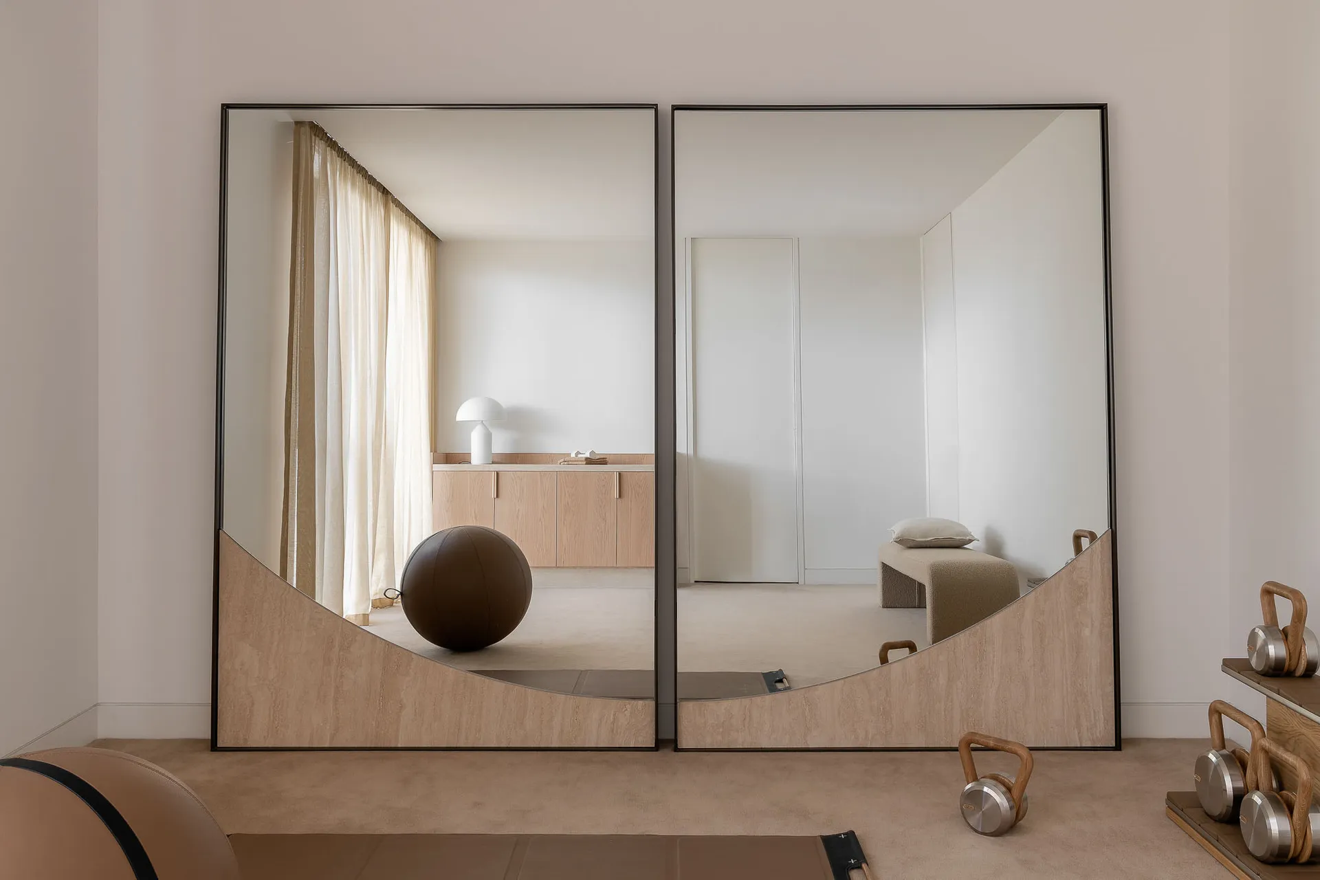 A minimalist interior with large mirrors and wooden elements.