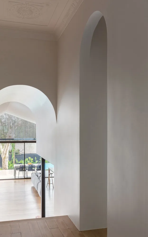Interior with minimalist design featuring white walls, arched doorways, and wooden flooring.