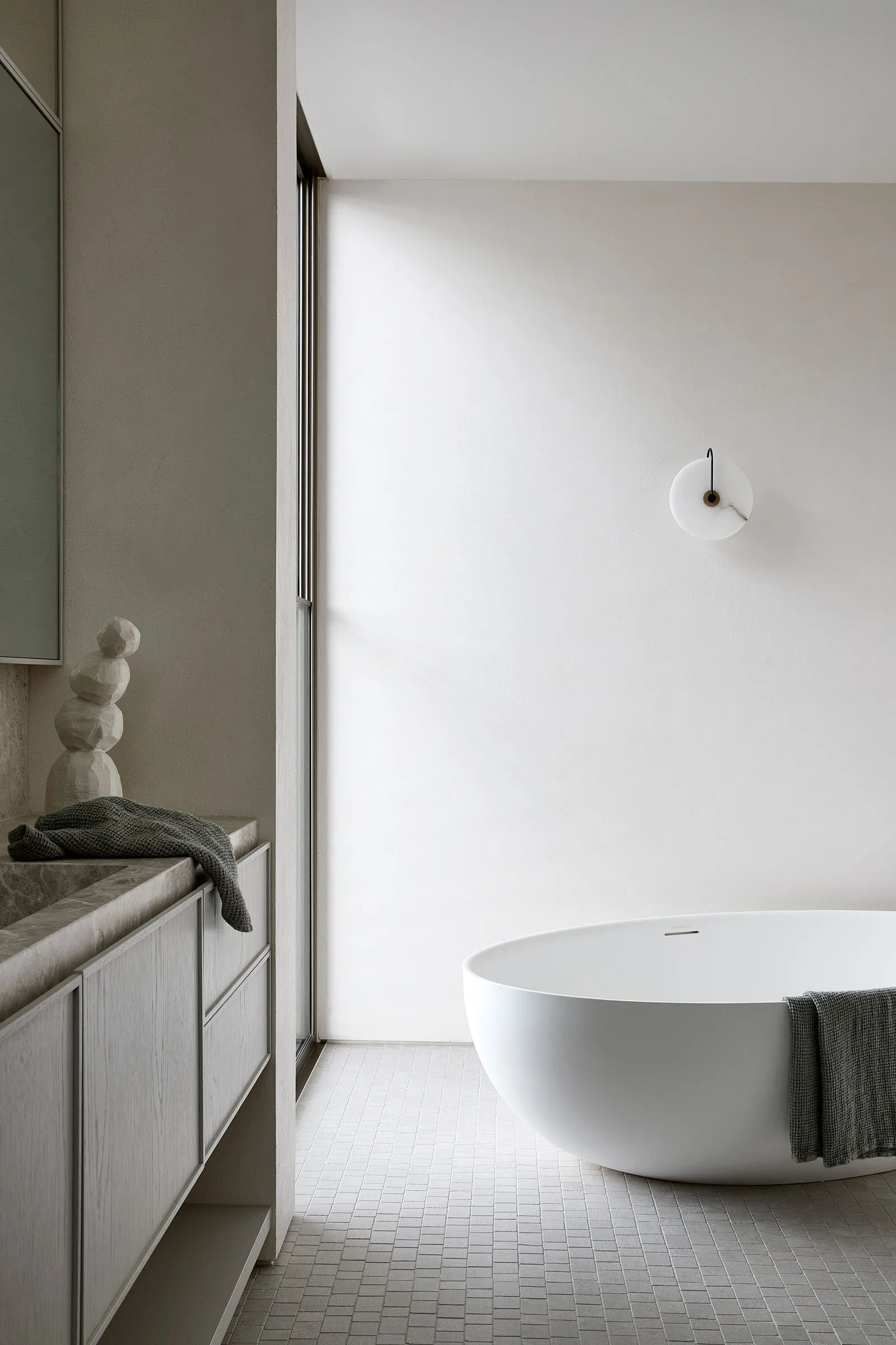 A minimalist bathroom with a ceramic bathtub, marble countertop, and metallic accents.
