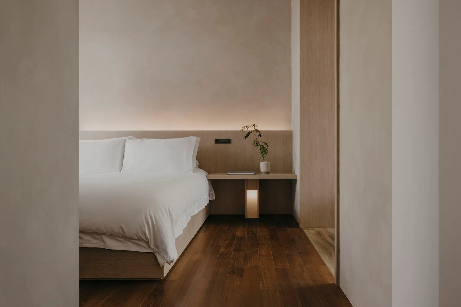 A minimalist bedroom featuring a wooden bed frame and flooring.
