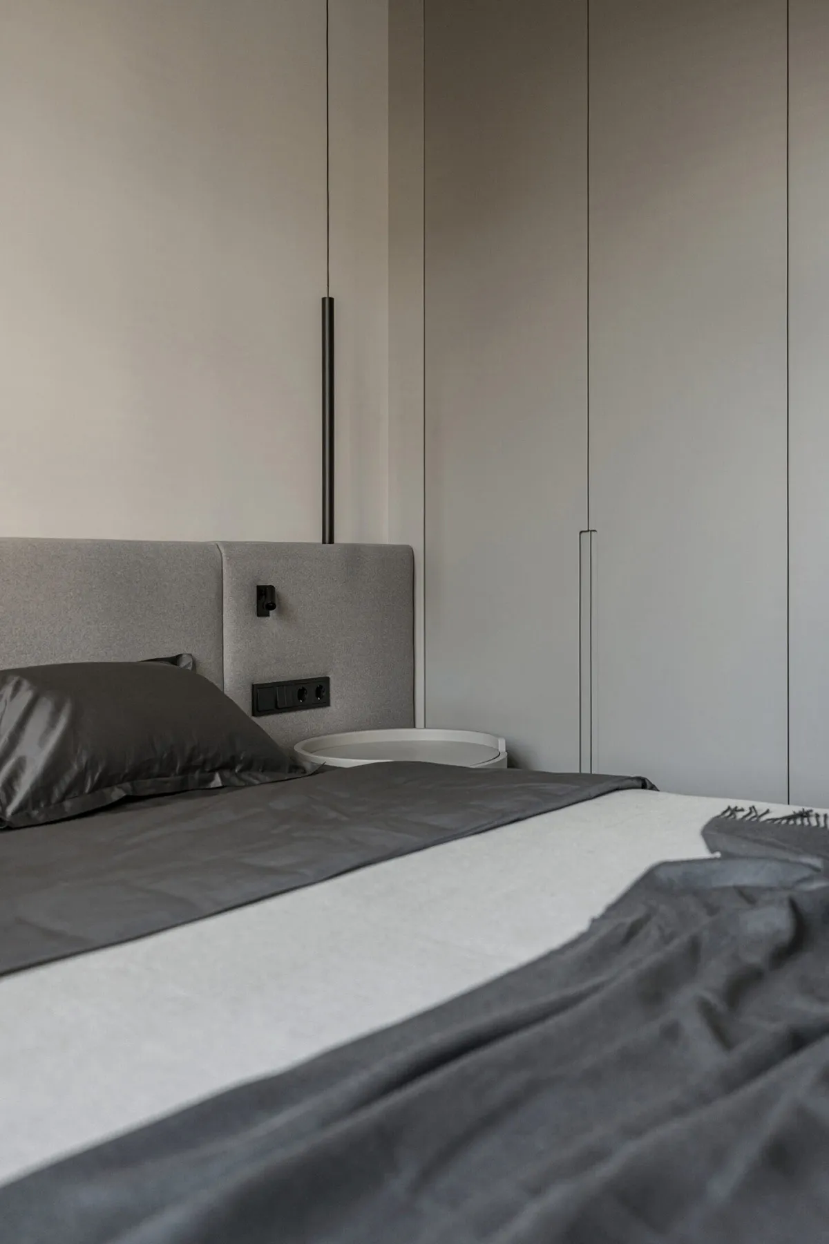 A modern bedroom featuring gray upholstered furniture and fabric materials.