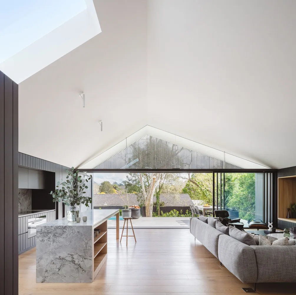 Modern house interior with marble kitchen island, concrete ceiling, and wooden floor.