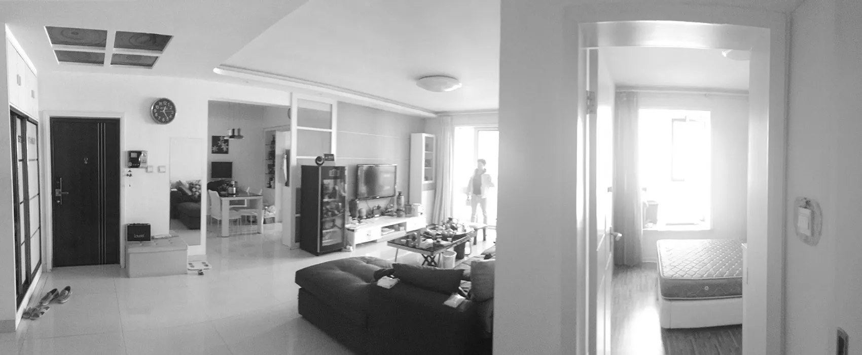 A modern living room with a black sofa, a glass cabinet, and a television in the background.