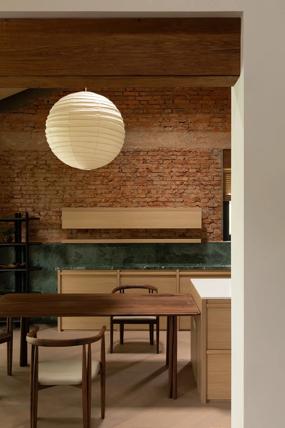Modern kitchen featuring wooden furniture, brick wall, and marble countertop