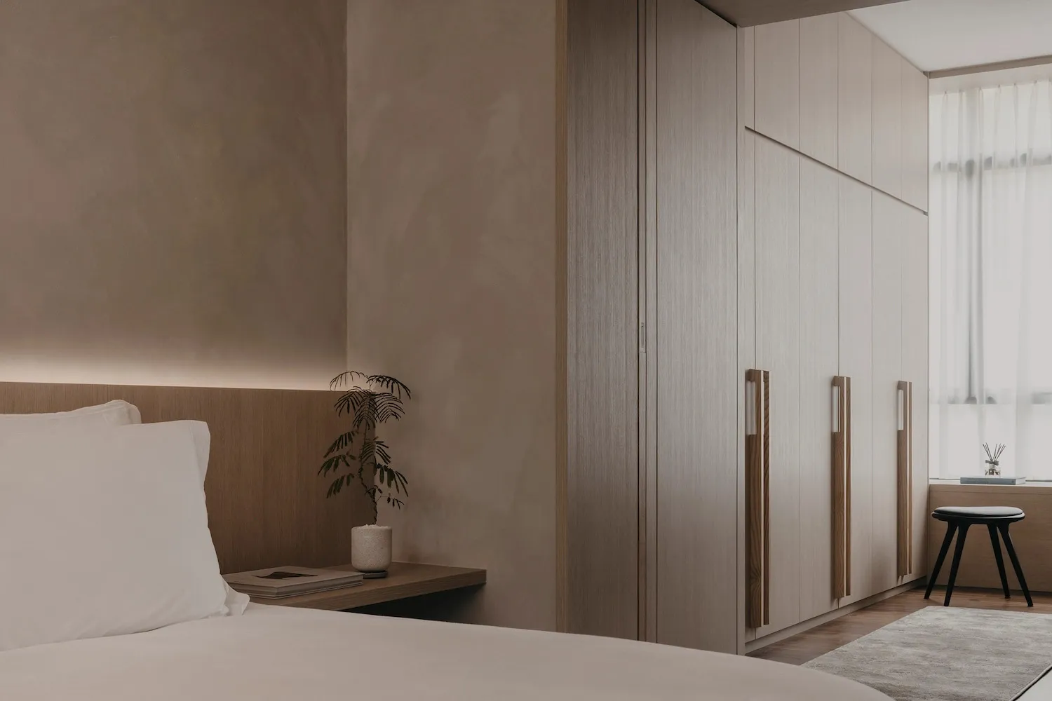 A modern minimalist bedroom with a wooden bed frame, a wooden headboard, and wooden furniture.