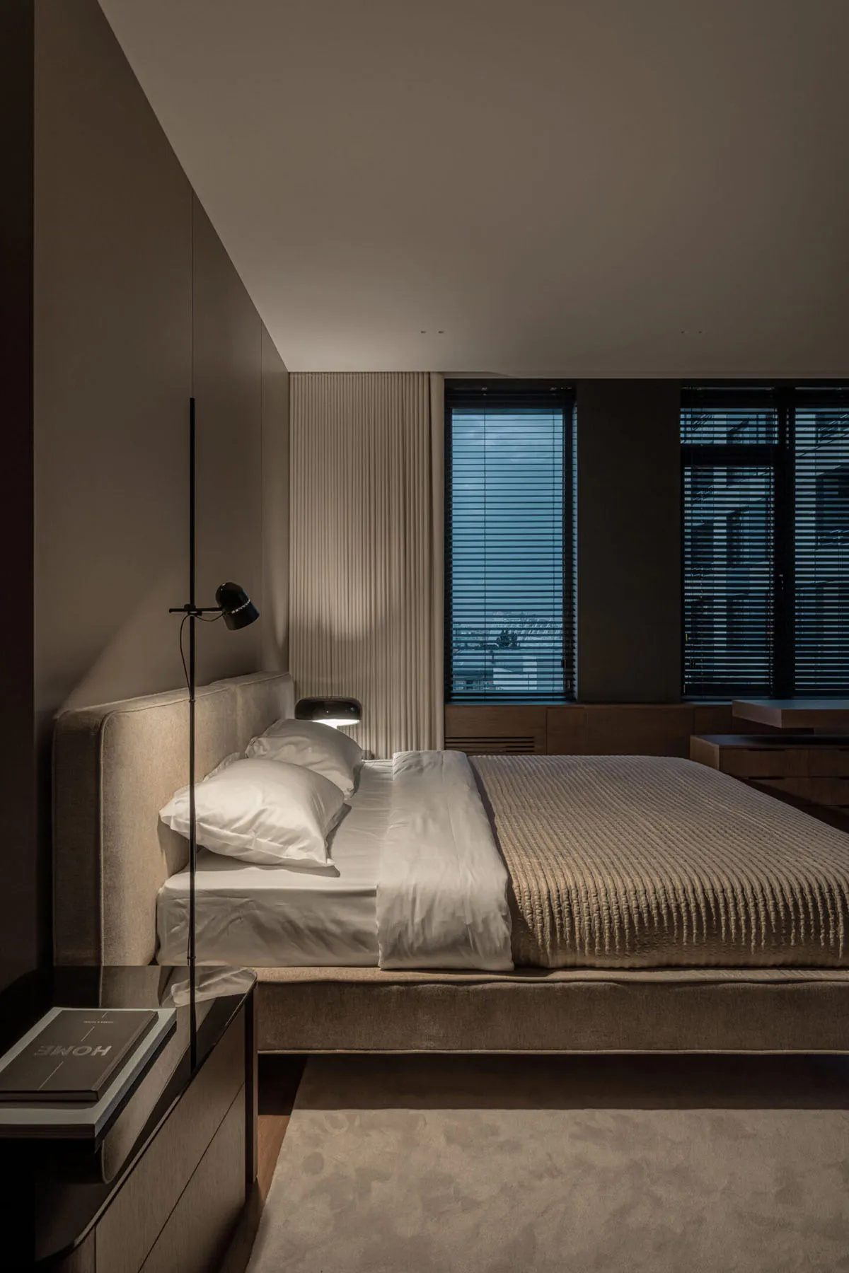 A modern minimalist bedroom with a fabric bed and a sleek side table.