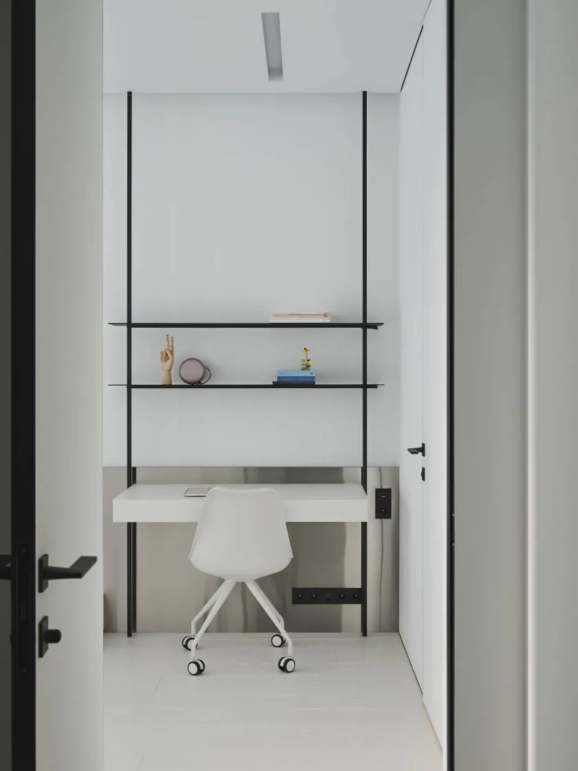 A minimalist white desk with a black metal frame in a minimalist environment.