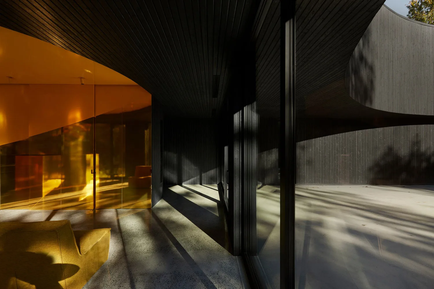 Modern living room with glass walls and floor-to-ceiling windows.