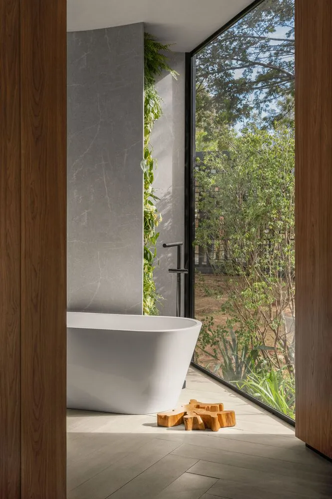 Modern bathroom interior featuring a freestanding bathtub, concrete walls, and large windows with natural light.