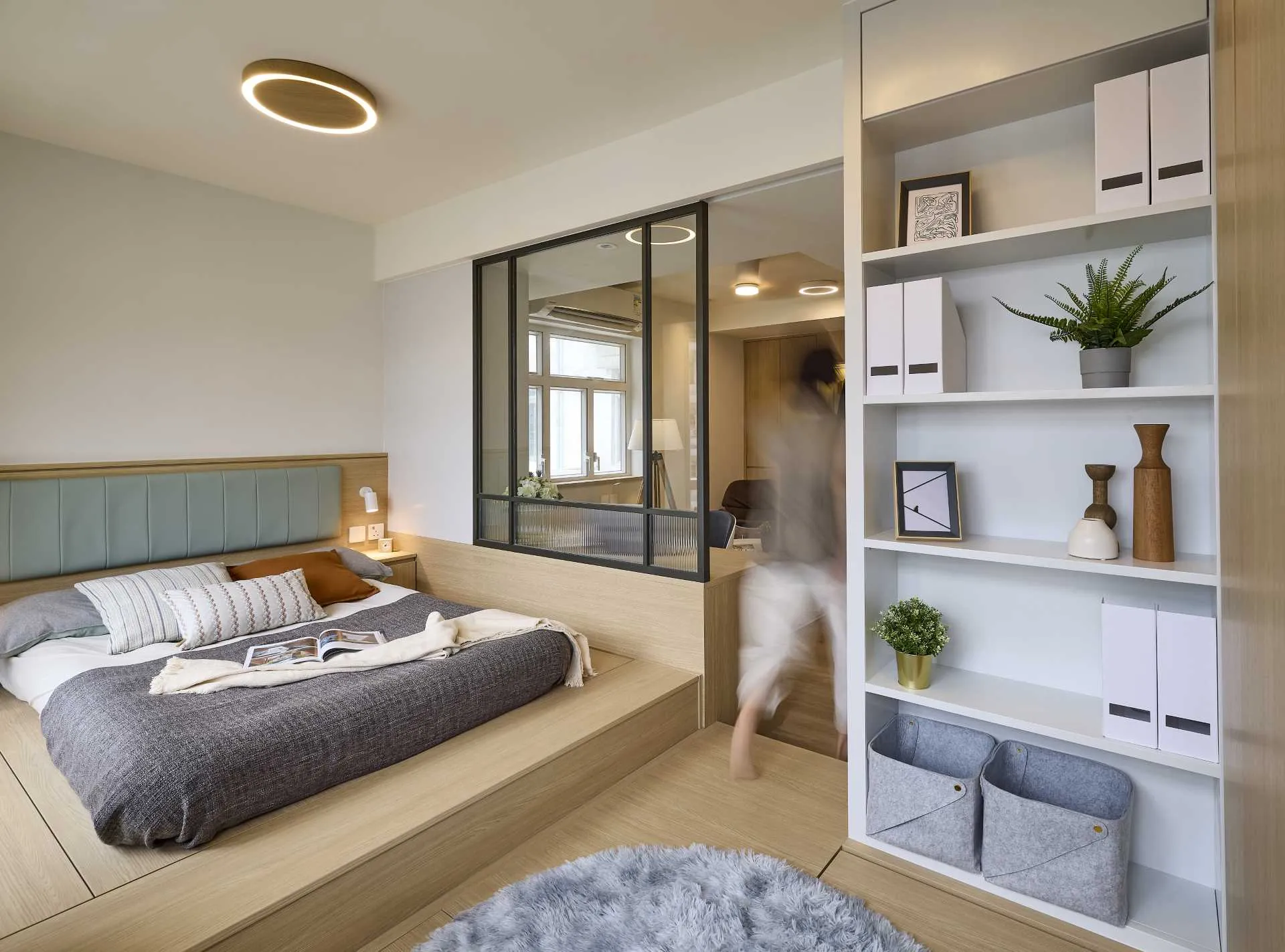 A modern bedroom featuring a wooden platform bed with leather cushions, a grey blanket, and a white and brown futon on a wood