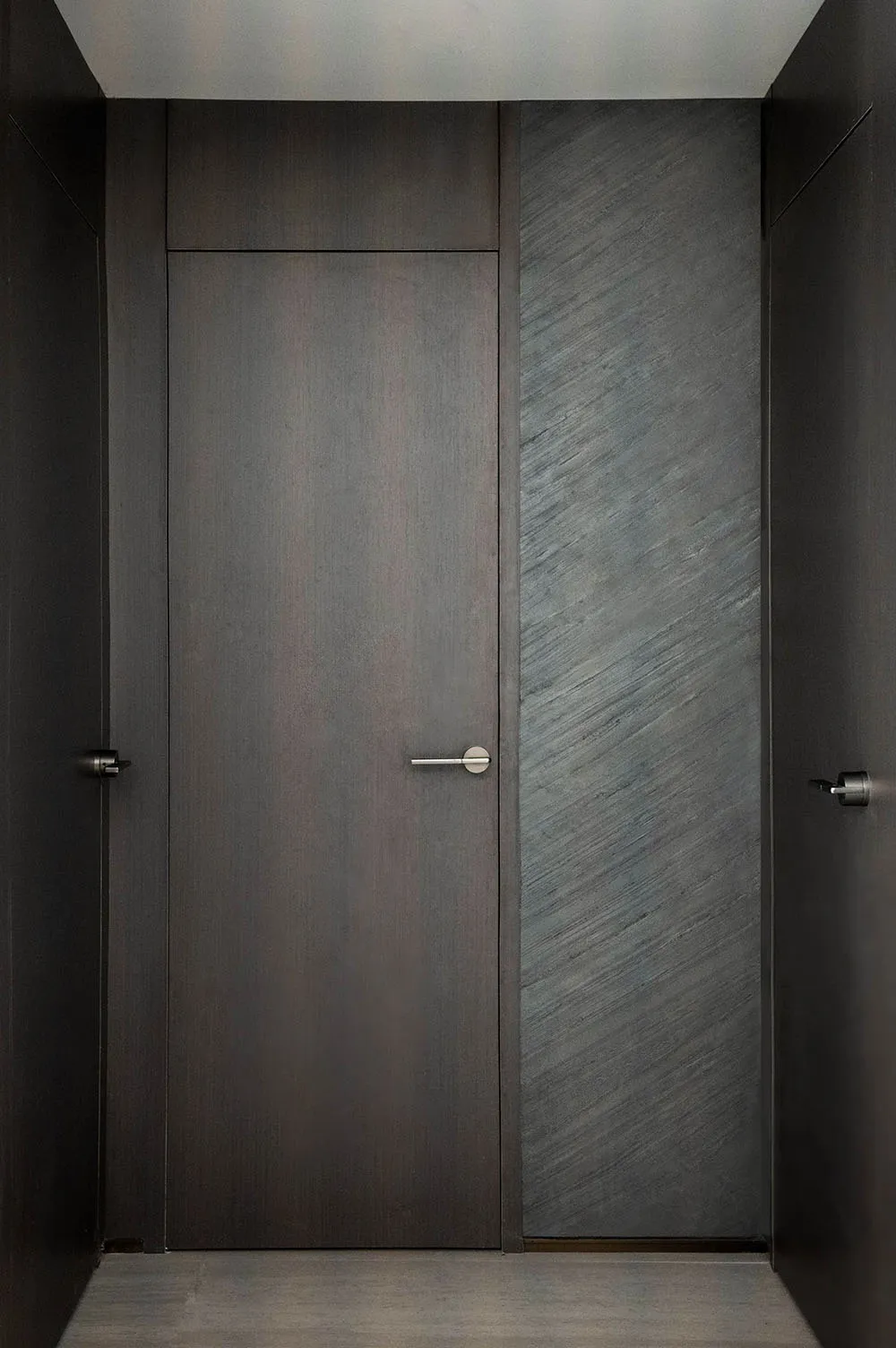 A modern dark door with a black marble core.
