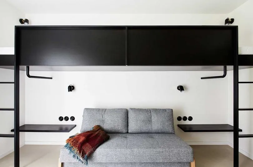 Clean, modern living room with black metal furniture, white walls, and a cozy sofa.