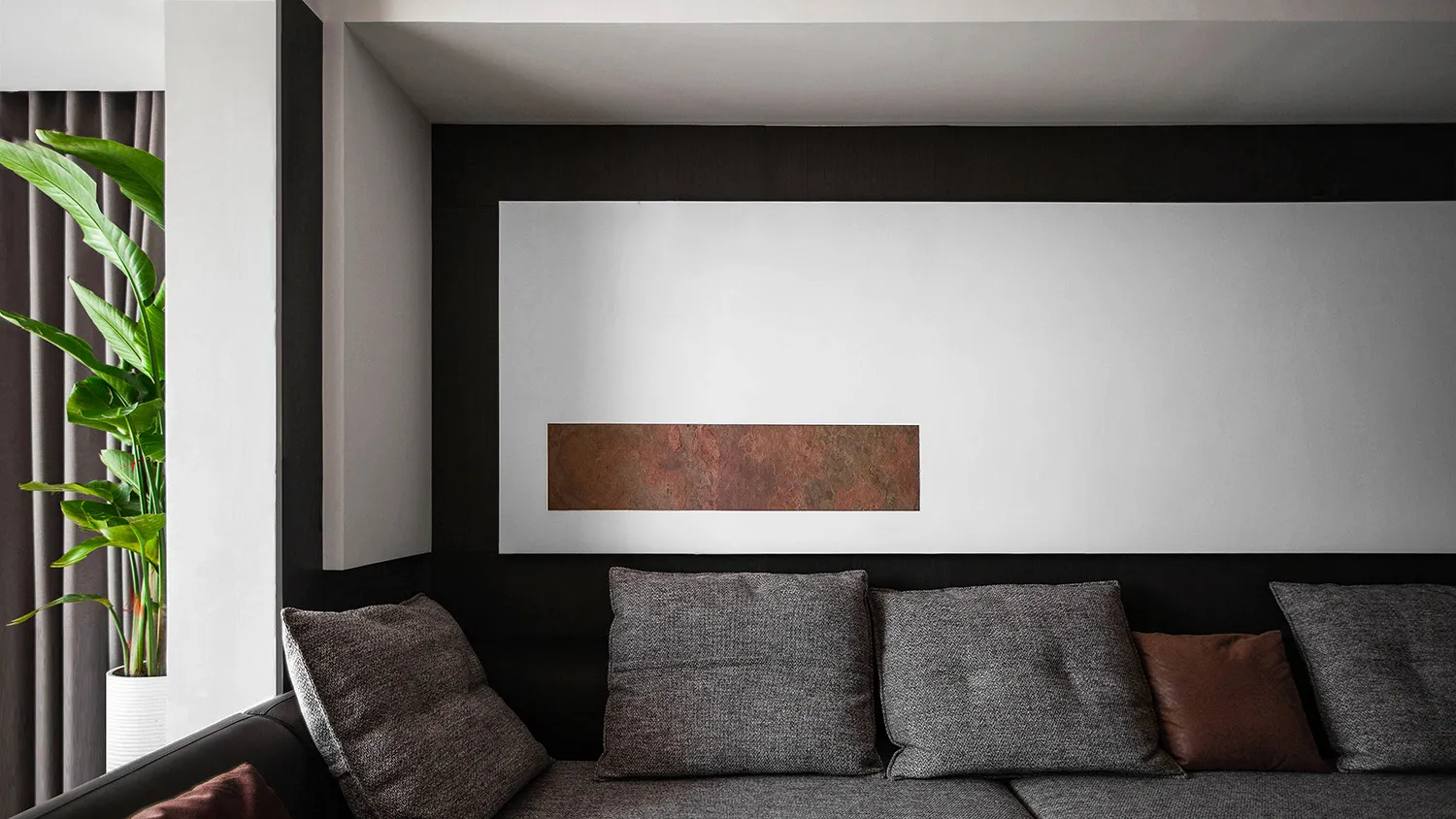 A modern, minimalist living room with a grey sectional sofa, grey throw pillows, and a minimalist interior design.