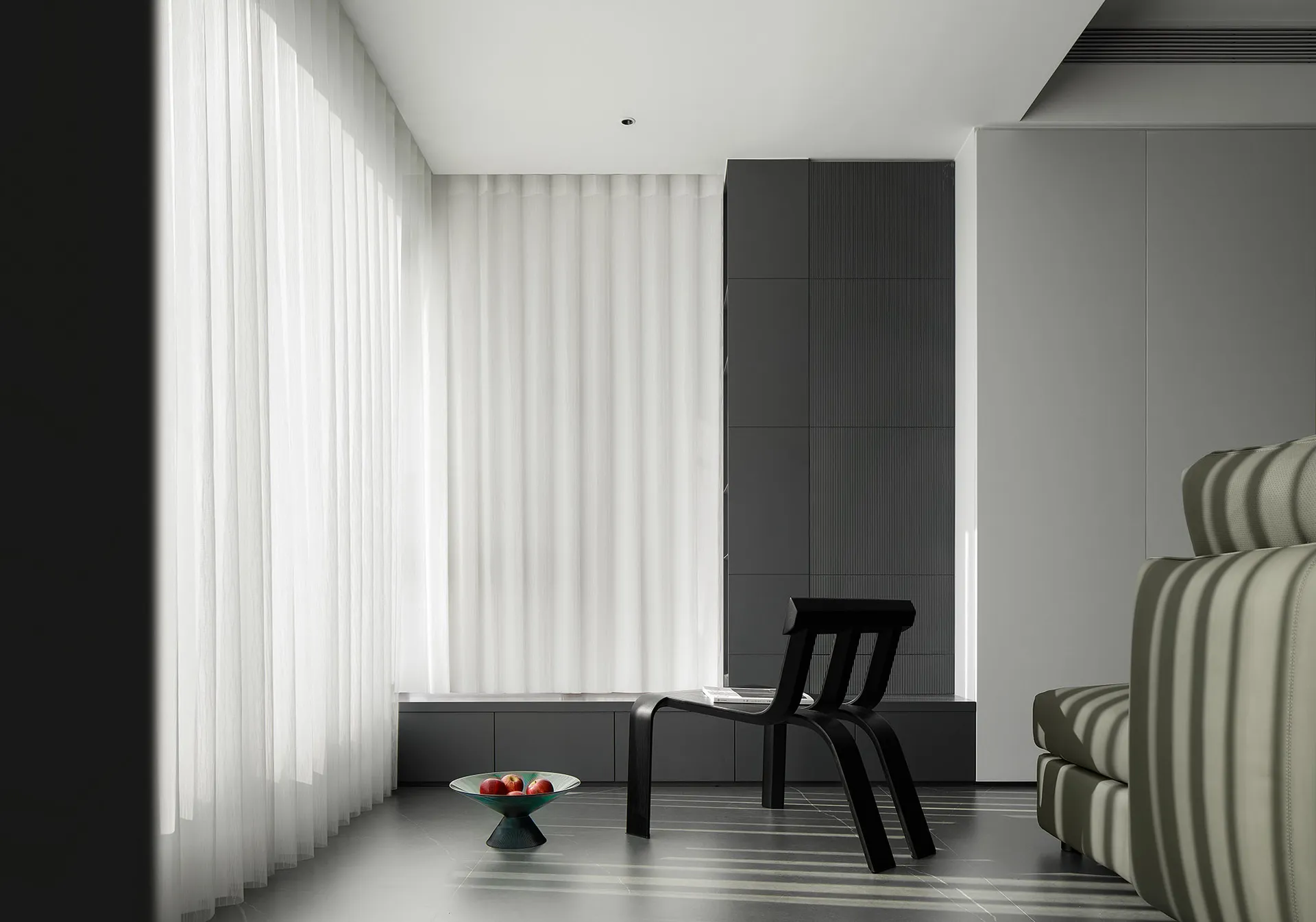 A modern minimalist living room with curtains, a black sculptural chair, and a white couch with vertical stripes.